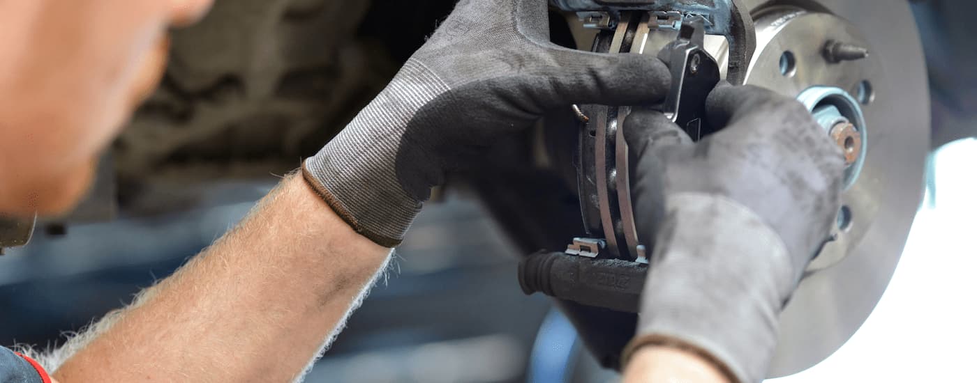 A close up of a mechanic working on a set of brakes.