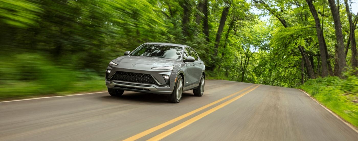 A grey 2024 Buick Envista Avenir is shown on a tree-lined road.