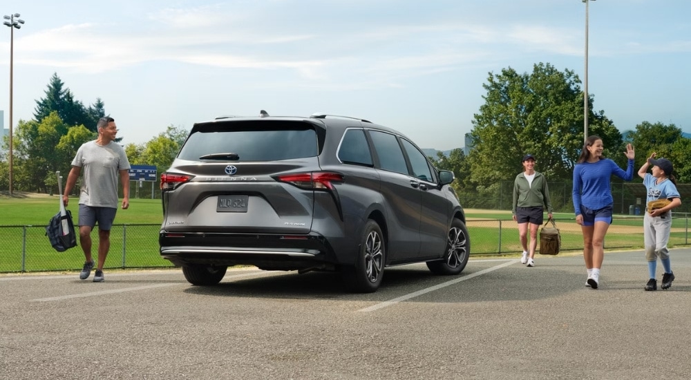 A grey 2025 Toyota Sienna Platinum is shown near a baseball field.