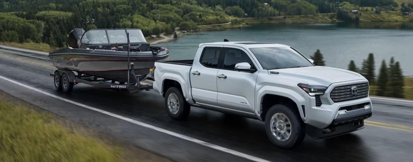 A white 2025 Toyota Tacoma Limited towing a boat after viewing a truck for sale near Cary.