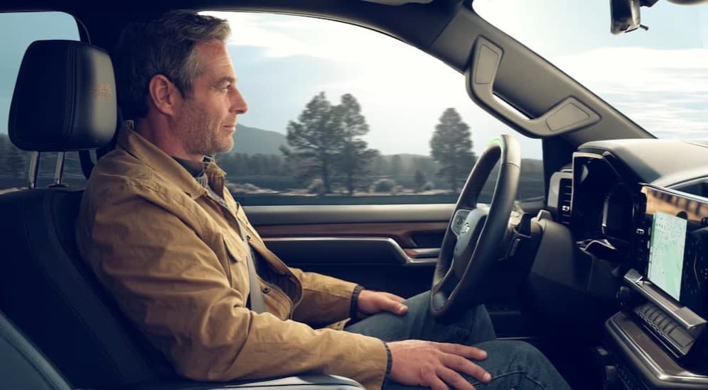 A person driving in a 2025 Chevy Silverado 1500 after viewing trucks for sale near Cary.