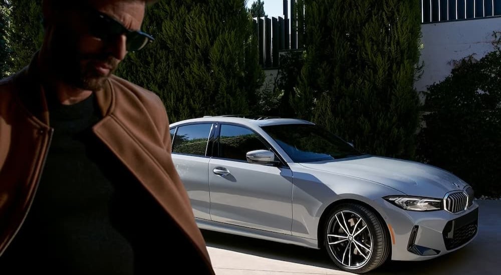 Man walking by a white 2024 BMW 3 Series parked by a car dealership near Cary.