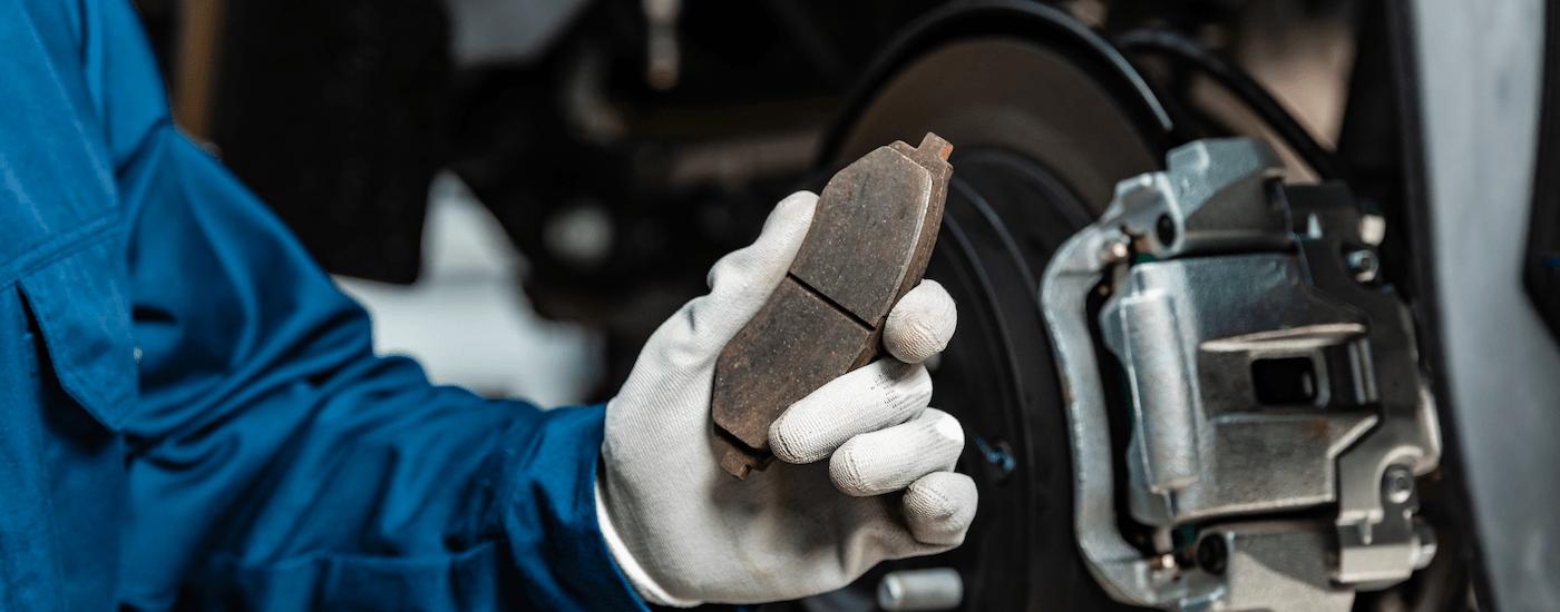 A mechanic is holding a brake pad for a vehicle.