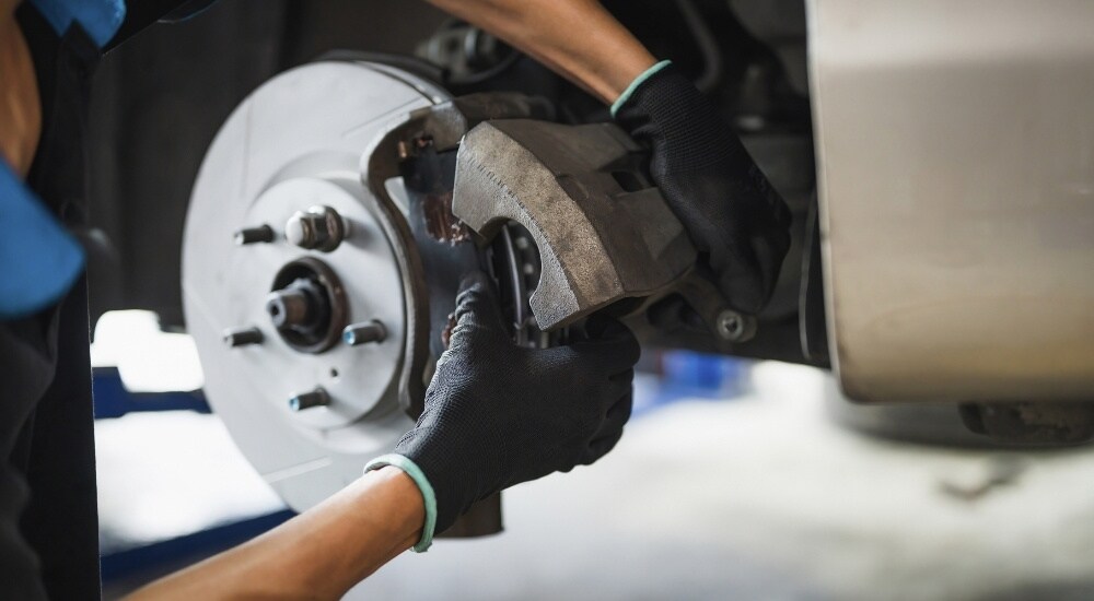 A mechanic is shown holding a caliper during a brake service in Charlotte.