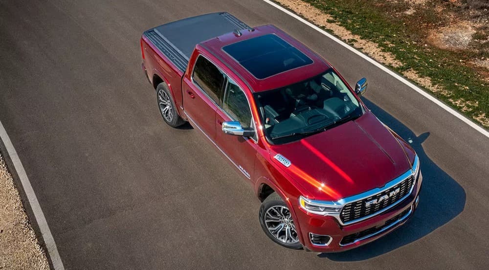 A red 2025 Ram 1500 is shown parked on a backroad.