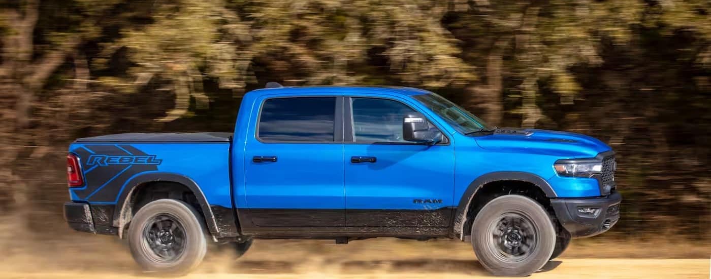 A blue 2025 Ram 1500 Rebel driving off-road.